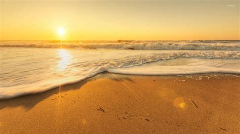 Golden sunset light reflecting on the waves reaching to the sand ...