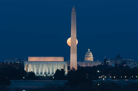 The Washington Monument Is Lit Up At Night In Front Of The Capitol
