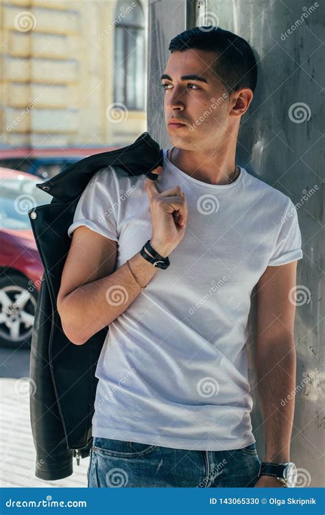 Young Handsome Guy In A White T Shirt Black Leather Jacket And Blue