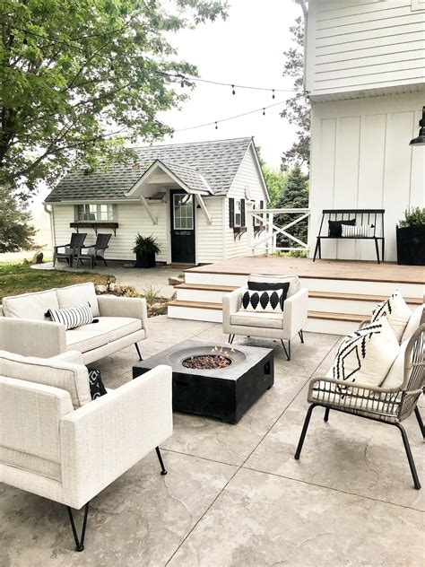 A Patio With Chairs Tables And A Fire Pit In Front Of A White House