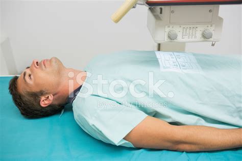 Male Patient Lying On An Examination Table While A Radiography Stock