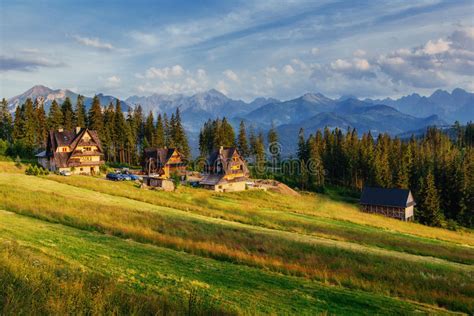 Traditional Wooden House In The Mountains On A Green Field Mount Stock