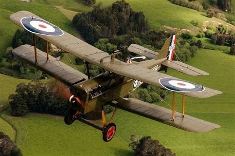 Vintage Ww1 Airplane Flying Over A Green Field