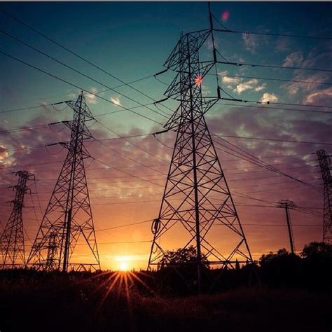 The Sun Is Setting Behind Power Lines In An Area With High Voltage