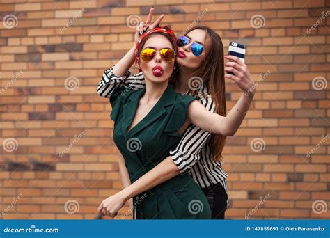 duas mulheres sexy novas da forma que levantam para o selfie e que riem com tonque retrato do