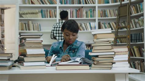 Concentrated African Woman Reading Book In The Library While African