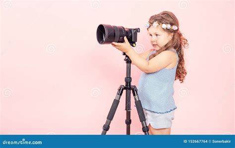 Little Girl Holding Camera And Smiling On Pink Background Stock Photo