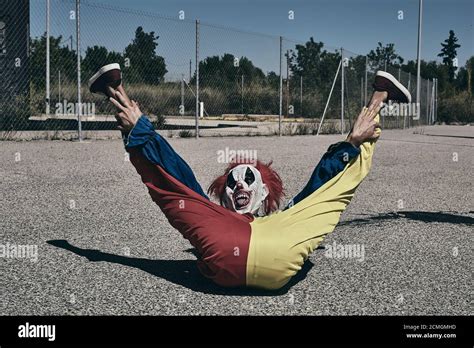 A Scary Clown Wearing A Yellow Red And Blue Costume Lying On The
