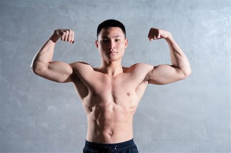 Hombre asiático musculoso posando sobre fondo gris Foto Premium