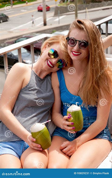 Two Young Women Having Fun And Drinking Cocktail In Summer Day Stock