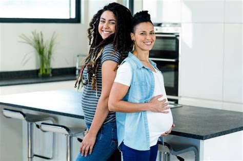 Pareja De Lesbianas Embarazadas De Pie De Espaldas Y Sonriendo En La