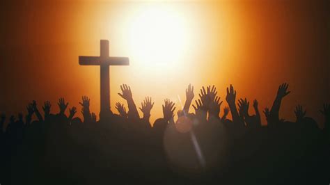 Silhouettes Of Hands Raised In Worship With Light Rays And Cross Stock