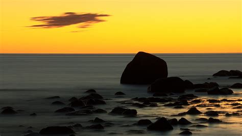 4k Free Download Stones Rocks On Ocean Waves Under Yellow Sky During