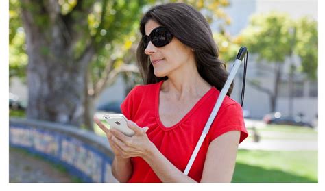 Blind Woman With Cane Using Her Iphone In A Park