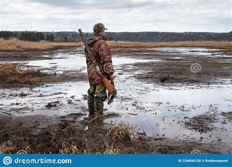 A Hunter Stands With A Downed Duck In His Hand In The Middle Of A