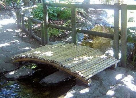 A Wooden Bridge Over A Small Stream In A Park