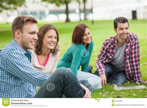 Casual Happy Students Sitting On The Grass Laughing Stock Photo Image