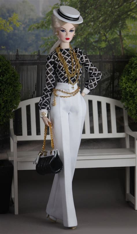 A Barbie Doll Wearing White Pants And A Black Top Holding A Handbag In