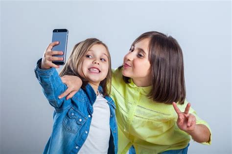 Premium Photo Two Sisters Posing And Taking Selfies In The Studio