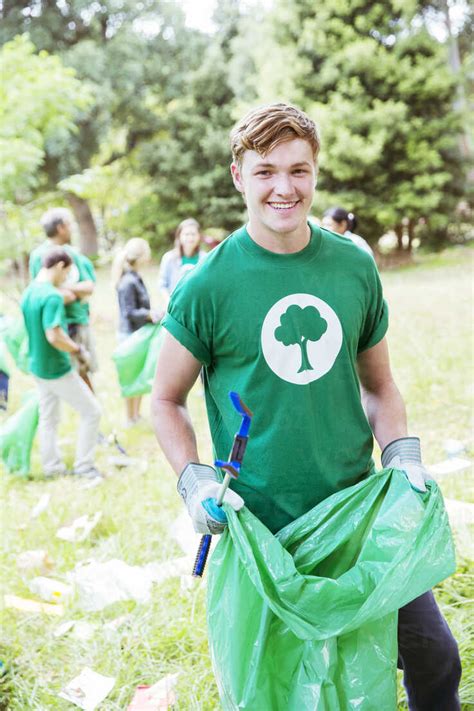 Portrait Of Smiling Environmentalist Volunteer Picking Up Trash Stock Photo