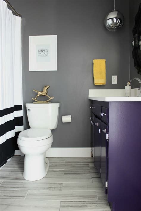 A minimalist bathroom with purple walls, a wooden floor and white appliances and a catchy shaped mirror. Something Will Always Go Wrong: The Hall Bathroom Remodel