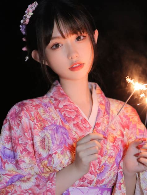 a woman in a kimono holding sparklers