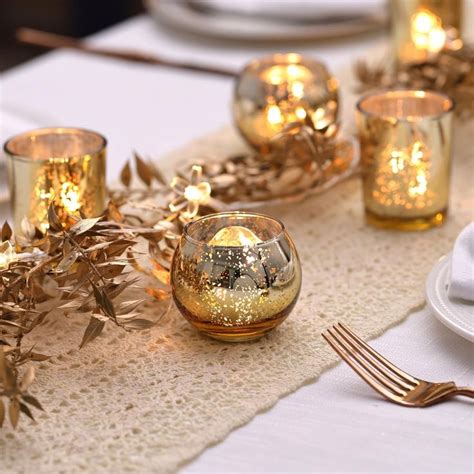 The Table Is Set With Gold Candles And Place Settings For Two People To