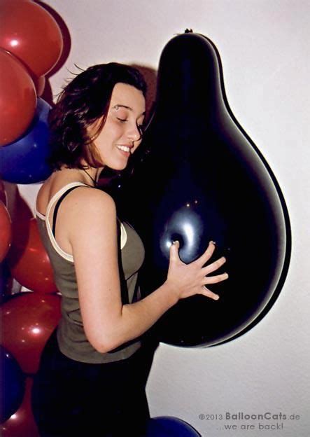 A Woman Holding A Giant Black Vase In Front Of Balloons
