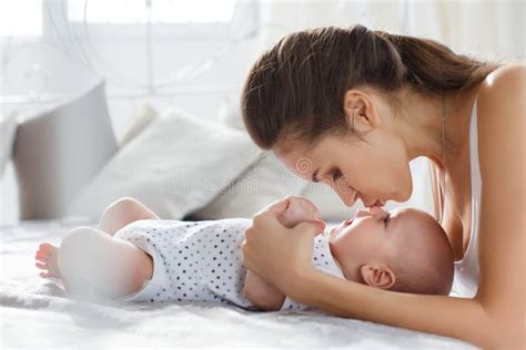 Mother Playing With Her Newborn Son Lying On Bed Stock Image Image Of