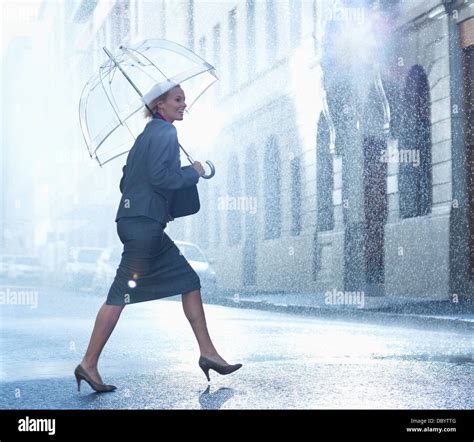 Happy Businesswoman With Umbrella Walking Across Rainy Street Stock