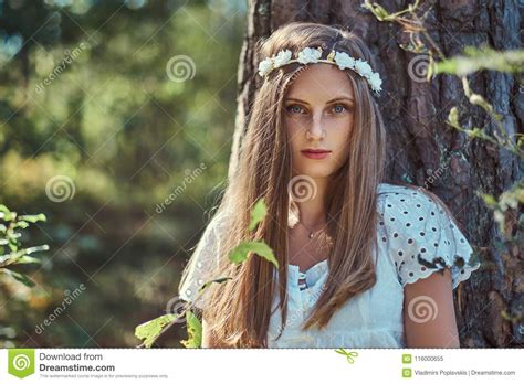 A Beautiful Woman In A White Dress And White Wreath On Head Posing In A Green Autumn Forest