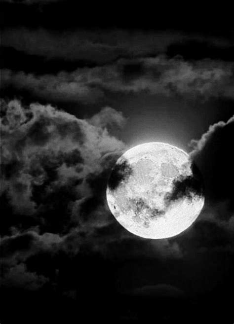 The Full Moon Is Seen Through Clouds In Black And White