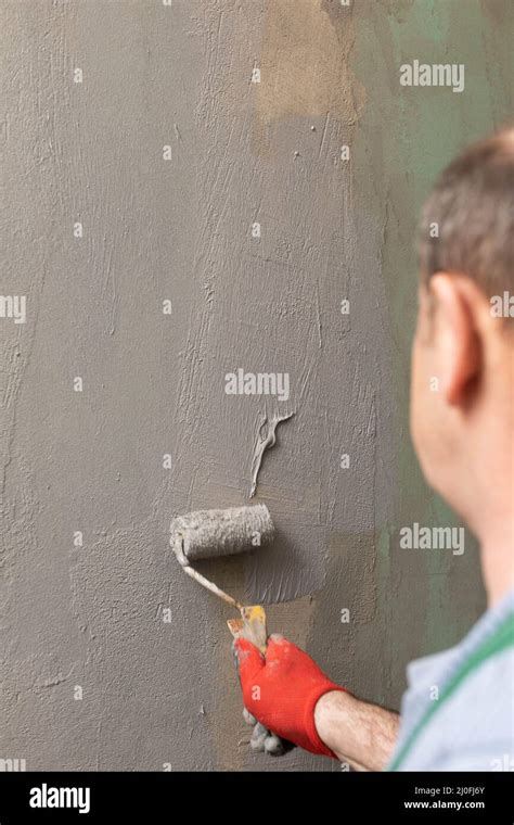 In The Bathroom A General Construction Worker Applies Moisture