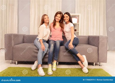 Trois Belles Jeunes Femmes Heureuses Assise Sur Le Divan Photo Stock