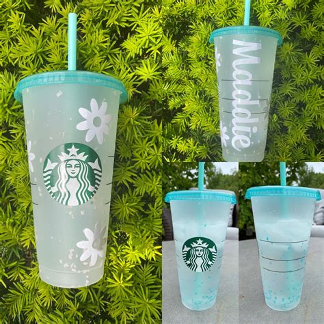 Three Starbucks Cups Sitting On Top Of A Table Next To Green Plants And