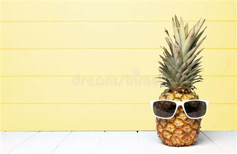 Summer Pineapple With Sunglasses Against A Soft Yellow Wood Background