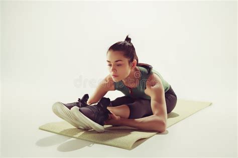 Beautiful Slim Brunette Doing Some Stretching Exercises In A Gym Stock