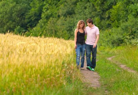 Young Couple Walking On The Road In A Field Of Wheat