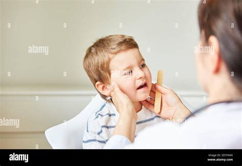Pediatrician Palpates Tonsils And Swollen Lymph Nodes In Children With