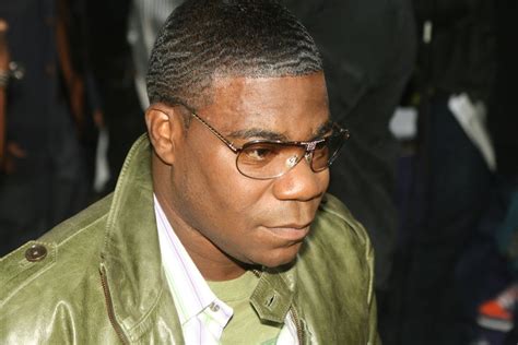 A Man Wearing Glasses And A Green Jacket Looks Off Into The Distance