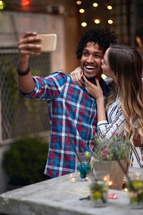 Afro American And Male Caucasian Female Taking Selfie In A Outdoor Bar