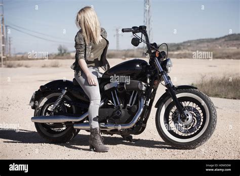 Blonde Teenage Girl On Black Motorcycle In Desert Looking Environment