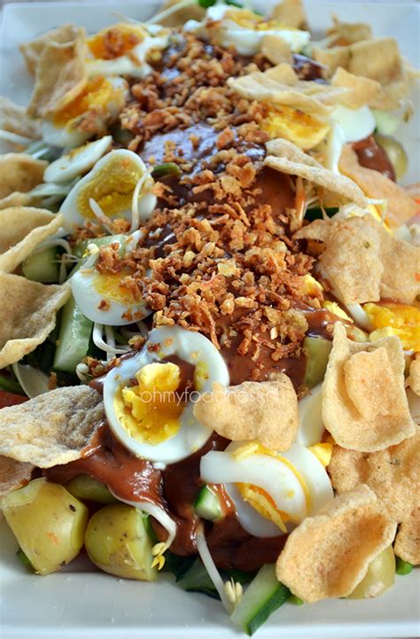 Gado gado definition, an indonesian dish consisting of raw or slightly cooked vegetables, as green beans, bean sprouts, and cabbage, with baked or boiled potatoes, served with a spicy peanut, chile, and coconut milk sauce. Gado Gado - OhMyFoodness