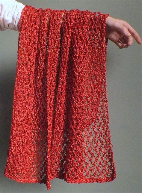 A Person Holding Up A Red Crochet Skirt With One Hand And The Other