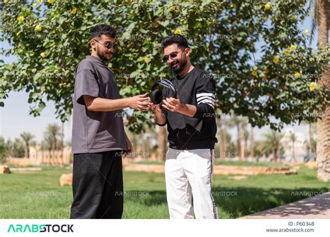 شابان عربيان سعوديان يرتديان النظارات الشمسية ويقضيان وقت ممتع سويا في الهواء الطلق، ممارسة نشاط