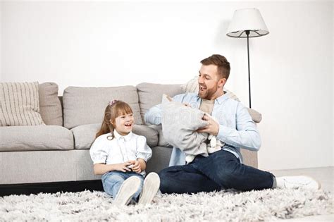 Girl With Down Syndrome And Her Father Sitting On A Floor And Talkiing