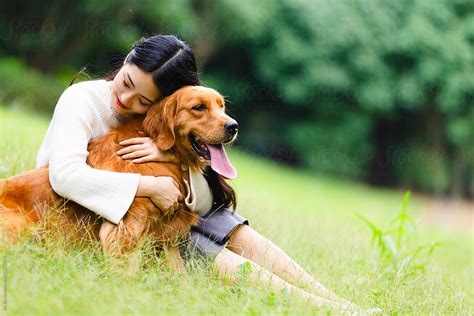 Happy Young Asianw Woman Holding Her Dog In The Park By Stocksy