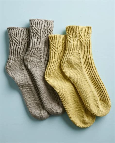 three pairs of socks sitting next to each other on a light blue surface with one yellow and the