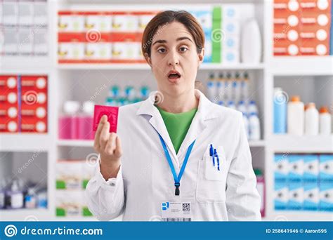 Brunette Woman Working At Pharmacy Drugstore Holding Condom Scared And