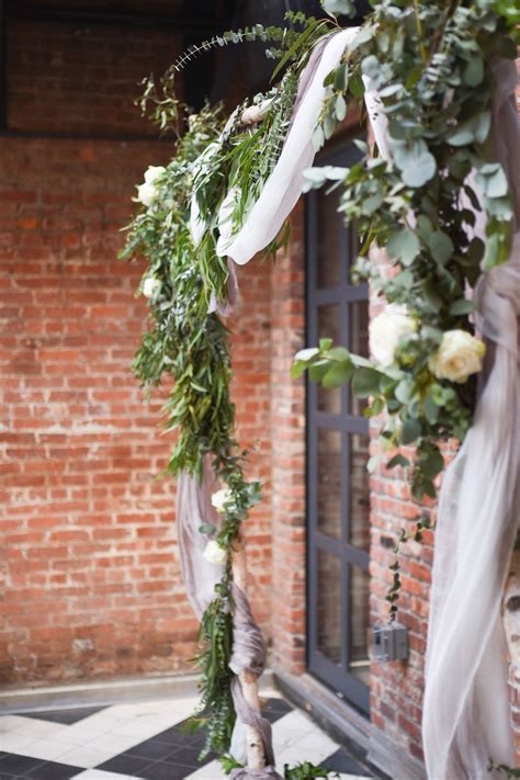 An Outdoor Wedding Ceremony With Greenery And Ribbons